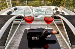 two glasses of wine sitting on a table next to a tub at Summer House Nika with Jacuzzi in Slime