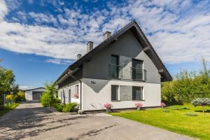 a white house with a black roof at Łasko - Wildlife Phototherapy 4 klimatyzowane wille, po 100m2, z dostępem do prywatnego stawu, ogrodu 2ha in Bierzwnik