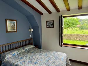 a bedroom with a bed and a window at Posada La Roblera in Oreña