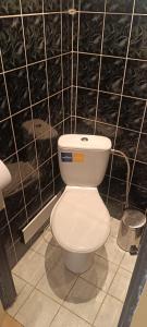 a white toilet in a black tiled bathroom at Orion in Mąchocice