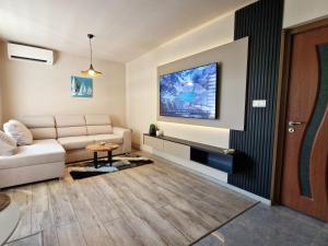 Una sala de estar con un sofá y un televisor en una pared. en Delux Apart Vulchevi with Parking, en Burgas