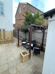 a wooden pergola with chairs and a tree on a patio at Flat 2, 297 Gillott Road, B16 0RT in Birmingham