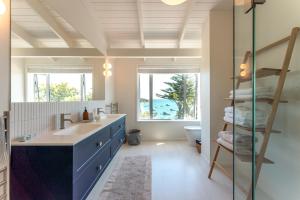 une salle de bain avec un lavabo et un miroir dans l'établissement Picnic Bay Vista - Be My Guest Waiheke, à Putaki Bay