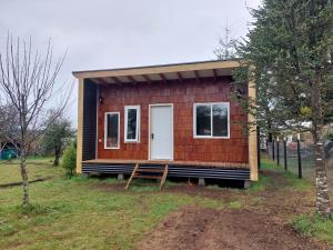 a tiny house sitting on top of a field at Cabañas El Roble in Dalcahue
