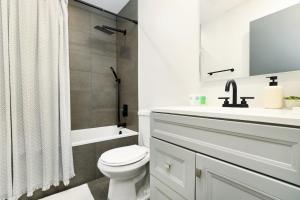 a white bathroom with a sink and a toilet at Chic & Cozy Condo in Manhattan with Free Parking & WiFi in Manhattan +12 photos