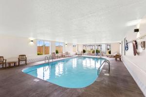 Una piscina con agua azul en una gran sala con mesas y sillas. en Best Western Airport Inn, en Moline