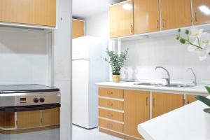 een keuken met houten kasten, een wastafel en een fornuis bij VM Sun & Beach in Almería