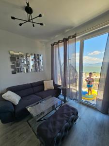 a living room with a couch and a large window at Lake Dream 1 in Sretenovo