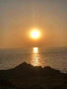 a sunset over the ocean with a rock in the foreground at Villaggio Malfidano in Buggerru
