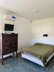 a bedroom with a bed and a tv and a dresser at Monoambiente Acantilados Single fin a 5 cuadras de la playa in Mar del Plata