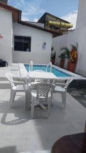 a white table and chairs next to a swimming pool at Apartamento na Passarela in Porto Seguro