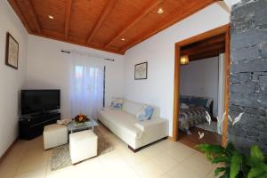 - un salon avec un canapé et une télévision dans l'établissement Casa da Bordadeira, à Arco da Calheta