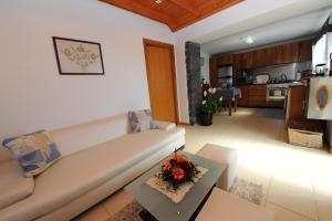 a living room with a white couch and a kitchen at BHF Residences Bordadeira in Arco da Calheta