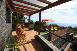 a patio with a table and chairs and an umbrella at BHF Residences Bordadeira in Arco da Calheta