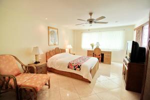 ein Schlafzimmer mit einem Bett, einem Fernseher und einem Stuhl in der Unterkunft BUTTERFLY GARDEN BOUTIQUE RESIDENCES by Frasier, A Lifestyle Destination Apt and Villas 1 to 3 Bedroom units, 2 Full Bathrooms, Rain shower, Spa bath, Complete kitchen, Staff 24-7,Fast fiber optic WIFI, 55" SMART TV's, Free BBQ, in Pattaya South