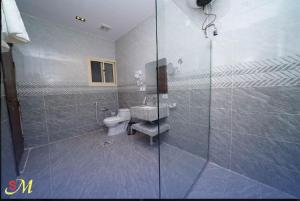 a bathroom with a toilet and a glass shower at شقق اس ام للشقق الفندقية in Hafr Al Baten