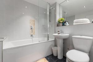 een witte badkamer met een toilet, een bad en een wastafel bij Westminster Classic Massionette in Londen