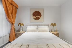 een slaapkamer met een groot wit bed met twee lampen bij Westminster Classic Massionette in Londen +10 foto's
