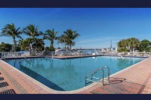 a large swimming pool with palm trees in a resort at Stylish 2 bedroom home Steps from private beach in Waveland