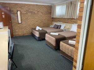 a hotel room with three beds and a tv at Buckaroo Motor Inn in Warwick