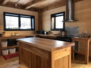 a kitchen with a large wooden island in a room at Maison ULTIMA ÉCO in LʼIslet