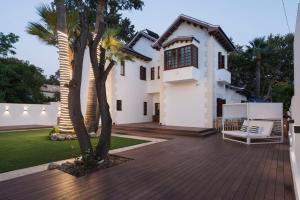 a white house with a deck and palm trees at La Moderna Suites in Málaga