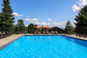 ein großer blauer Swimmingpool mit Liegestühlen und Bäumen in der Unterkunft La Bannik in Ville-Marie