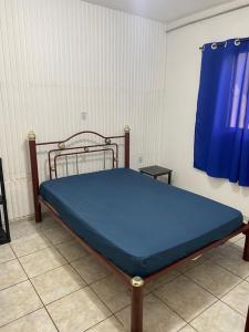 een bed in een kamer met een blauw laken bij Refúgio no Centro da Cidade in Águas de Lindóia