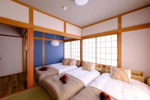 eine Reihe von 4 Betten in einem Zimmer mit Fenstern in der Unterkunft Board Game House Tokyo in Tokio