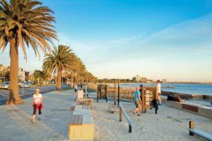 een groep mensen die op een strand met palmbomen rent bij Sensational St Kilda stay at Sunset Beach Tower in Melbourne