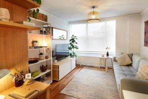 een woonkamer met een bank en een televisie bij Sensational St Kilda stay at Sunset Beach Tower in Melbourne