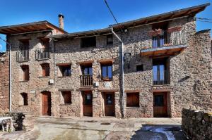 LlagunesにあるRefugi Rural Vall de Siarbの木製のドアと窓のある古い石造りの建物