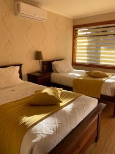 ein Hotelzimmer mit zwei Betten und einem Fenster in der Unterkunft Hotel Pitrufquen in Pitrufquén