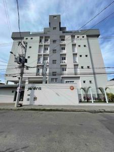 a large white building on the side of a street at Apê 212 - Piscina, Churrasqueira, 2 Quartos a 600m da Orla Central in Ubatuba