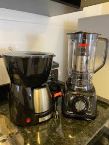 a blender sitting on a counter next to a coffee maker at Apê 212 - Piscina, Churrasqueira, 2 Quartos a 600m da Orla Central in Ubatuba