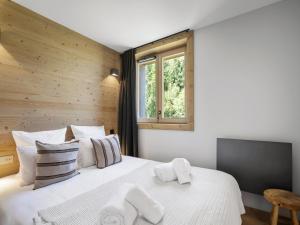 una camera da letto con un grande letto bianco e una finestra di Appartement skis aux pieds avec 6 couchages adultes et espace bien-être - FR-1-562-82 a Courchevel