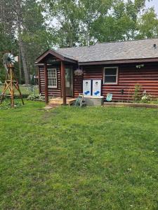 a log cabin with a windmill in the yard at Butler's Bay Cottage cottage in Hayward