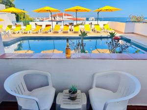 two chairs and a table next to a swimming pool at Vila Bela Hotel in Albufeira