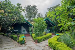 兰纳加Corbett Nature Retreat的一座带遮阳伞的建筑前的花园