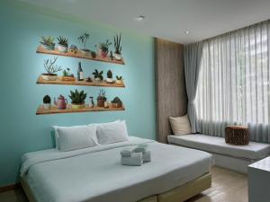 a bedroom with a bed and a window with plants on shelves at Beat Hotel Bangkok in Bangkok