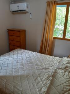 a bedroom with a bed with a dresser and a window at Casa familiar de dos plantas in Guaymallen
