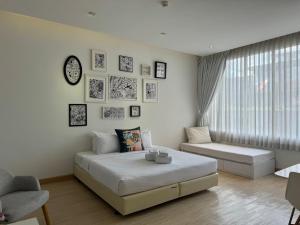 a white bedroom with a bed and a couch at Beat Hotel Bangkok in Bangkok