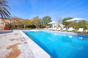 a swimming pool with white chairs and umbrellas at Agroturisme Rafal Nou in Manacor