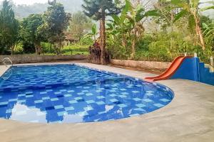 a swimming pool with a slide and a blue tiled floor at Urbanview Resort Syariah Batu Hijau Cilember Puncak in Cisarua