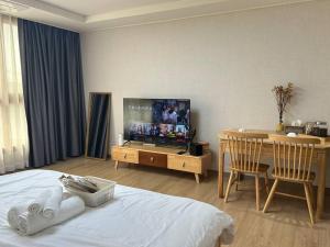 a bedroom with a bed and a table and a television at D' Heights Monterrace Lake Condo in Mabalacat