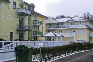 a yellow building with a white fence in front of it at Villa Laura 12 in Kühlungsborn