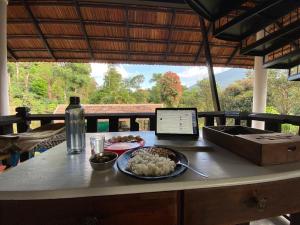 a table with a plate of food and a laptop at T Stop Farmhouse Coorg in Kurchi +55 photos