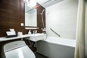 a bathroom with a sink and a toilet and a tub at Hotel Quest Shimizu in Shizuoka