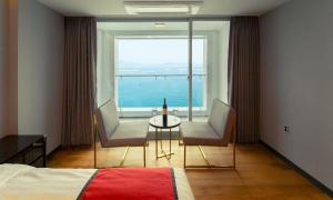 Una habitación de hotel con una cama, una mesa y sillas. en Venezia Hotel and Suite, en Yeosu