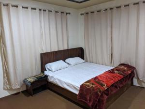 a bedroom with a bed with white sheets and curtains at Alpine Resort Khaplu in Khaplu
